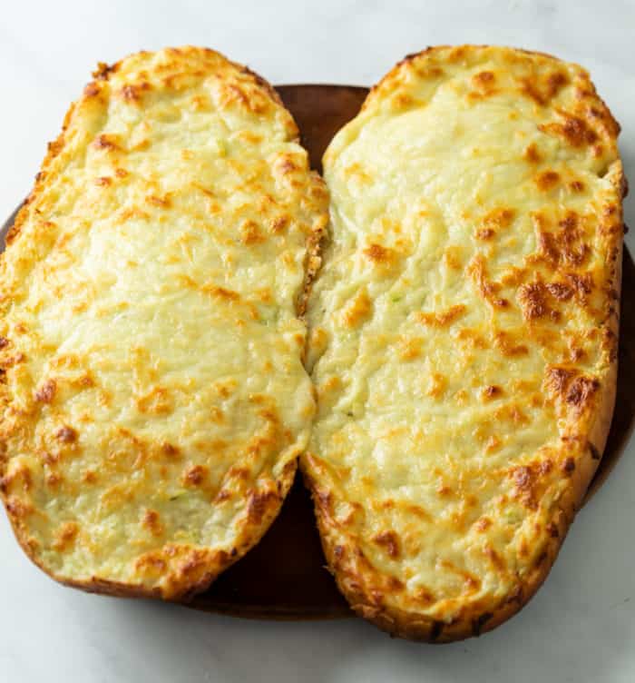 French bread topped with Garlic Butter and Melted Cheese before slicing to make Garlic Bread with Cheese.