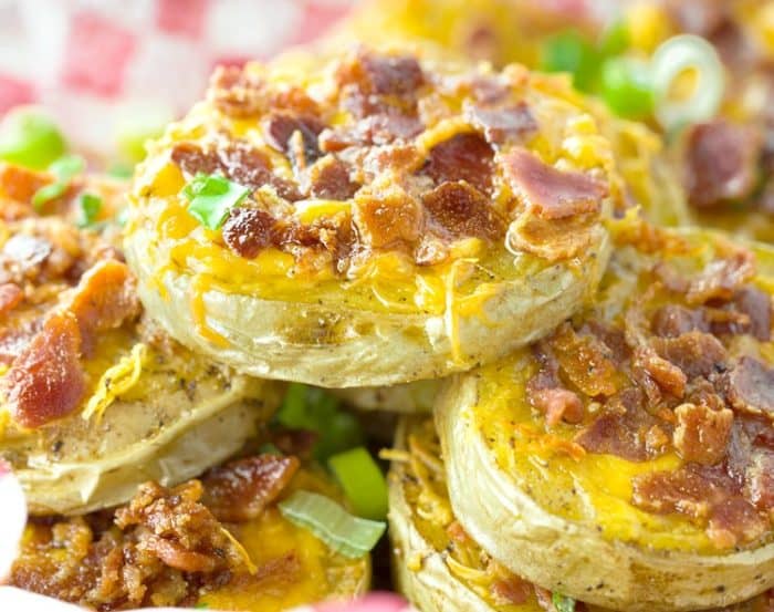 A pile of baked potato slices topped with melted cheese and crispy bacon.