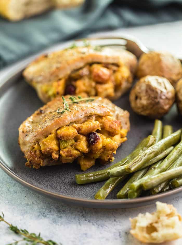 Seasoned Baked Pork Chops filled with Stuffing on a plate with green beans and roasted potatoes