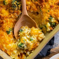 broccoli chicken rice casserole in a casserole dish with a wooden spoon in it.