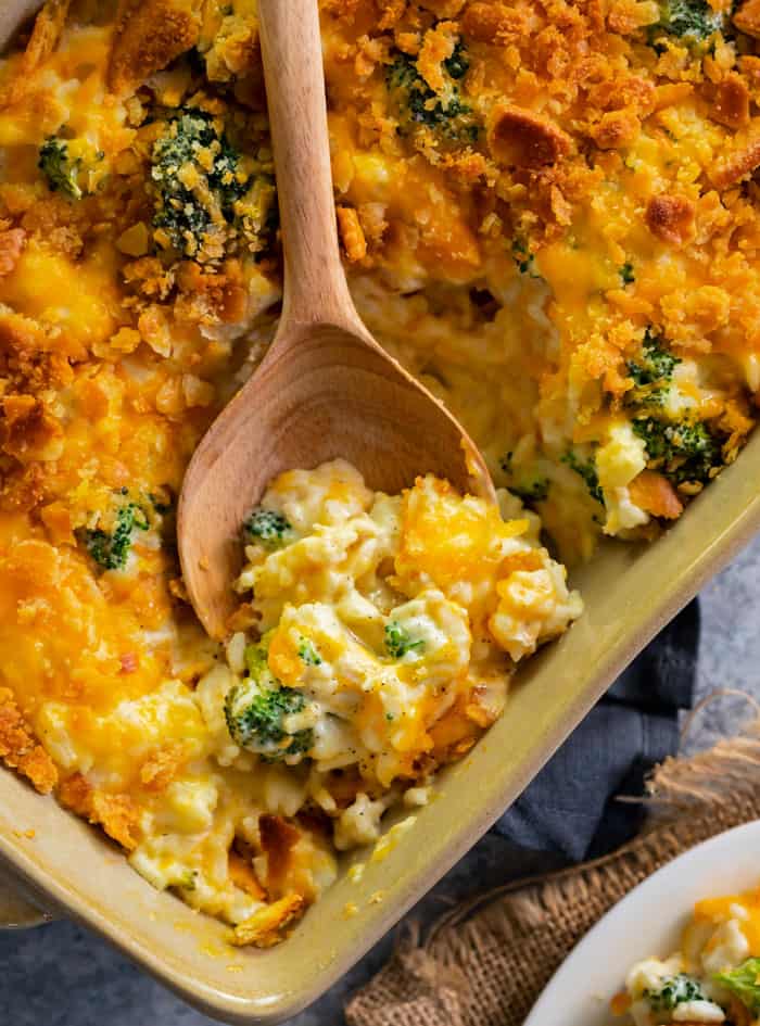 overhead shot of broccoli cheddar chicken and rice casserole with wooden spoon in the dish.