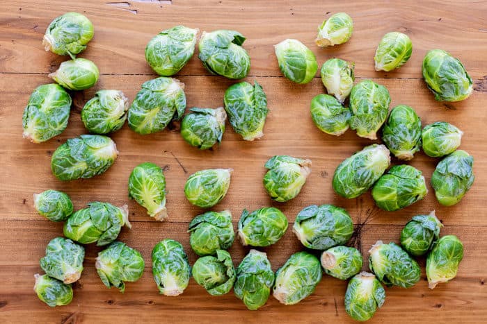 whole, uncooked Brussels sprouts on a wooden table.