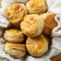 A bowl of buttermilk biscuits with a cloth underneath.