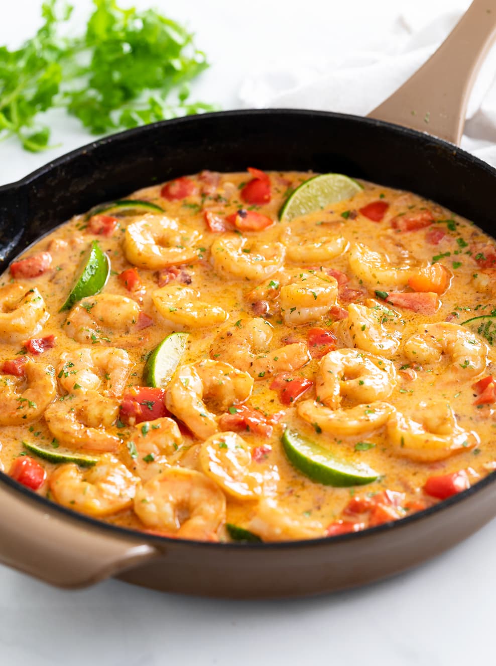 A skillet filled with Cajun Shrimp in a Cajun sauce with cilantro in the background.