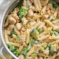 A big pot filled with Chicken and Broccoli Pasta with lemon slices on the side.