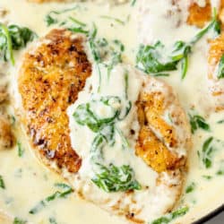 A chicken breast in a skillet with creamy Chicken Florentine sauce with spinach.