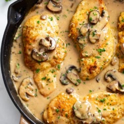 Chicken Marsala in a skillet with marsala sauce, mushrooms, and parsley.