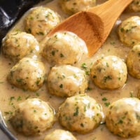Chicken Meatballs in a skillet with sauce and parsley on top.