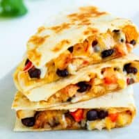A stack of chicken quesadillas filled with melted cheese, black beans, and peppers.