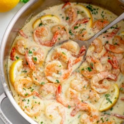Creamy Garlic Shrimp in a skillet with lemons and chopped parsley.