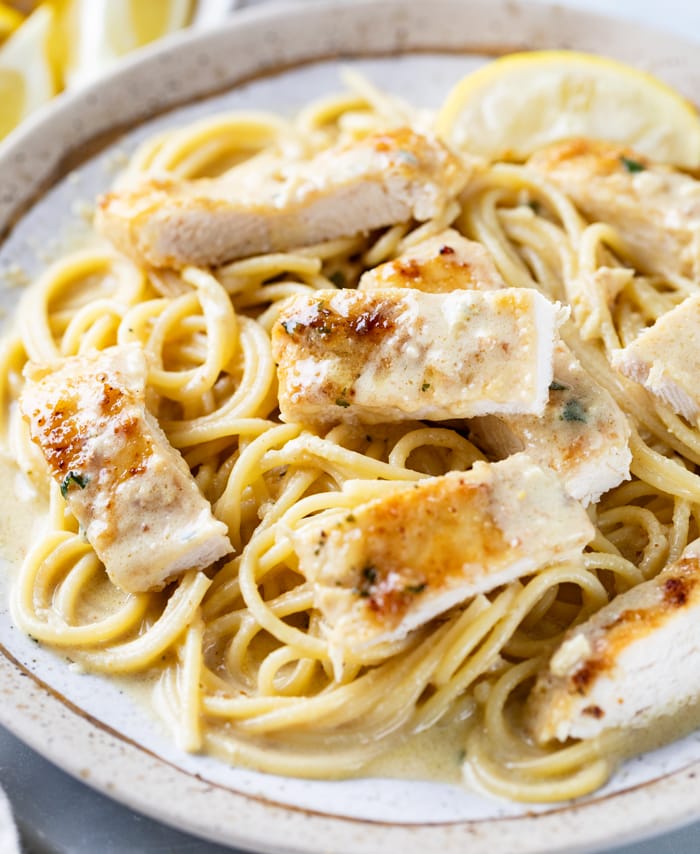 A plate with Creamy Lemon Chicken on top of Spaghetti pasta.
