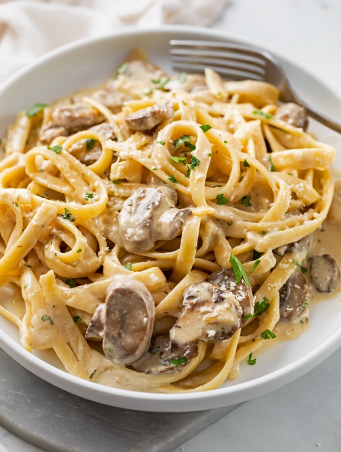 A white plate with Fettuccine Noodles in a Creamy Mushroom Sauce.