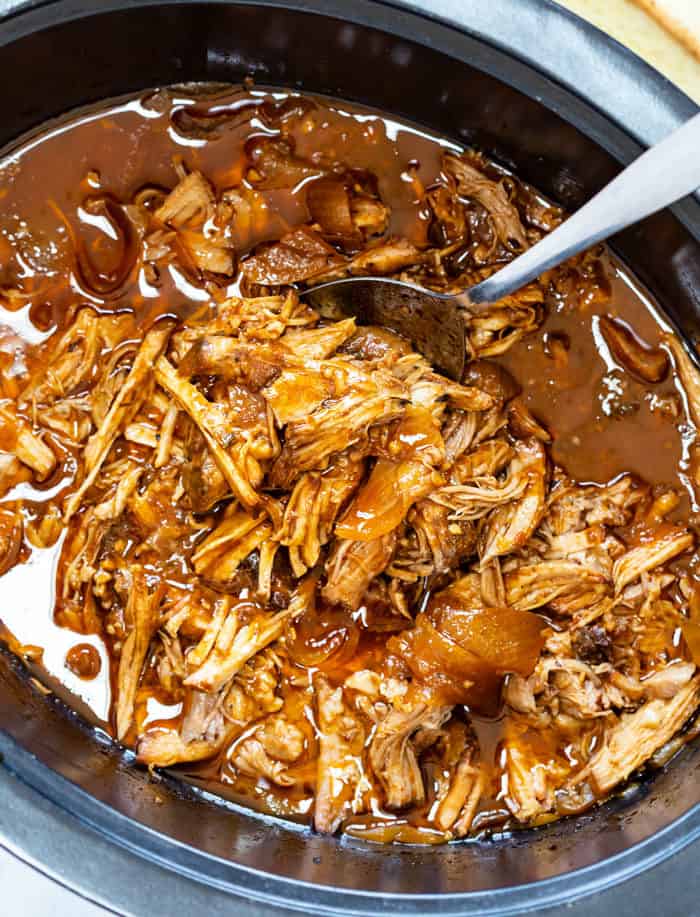 Pulled Pork in the Crock Pot with a Spoon scooping it up.