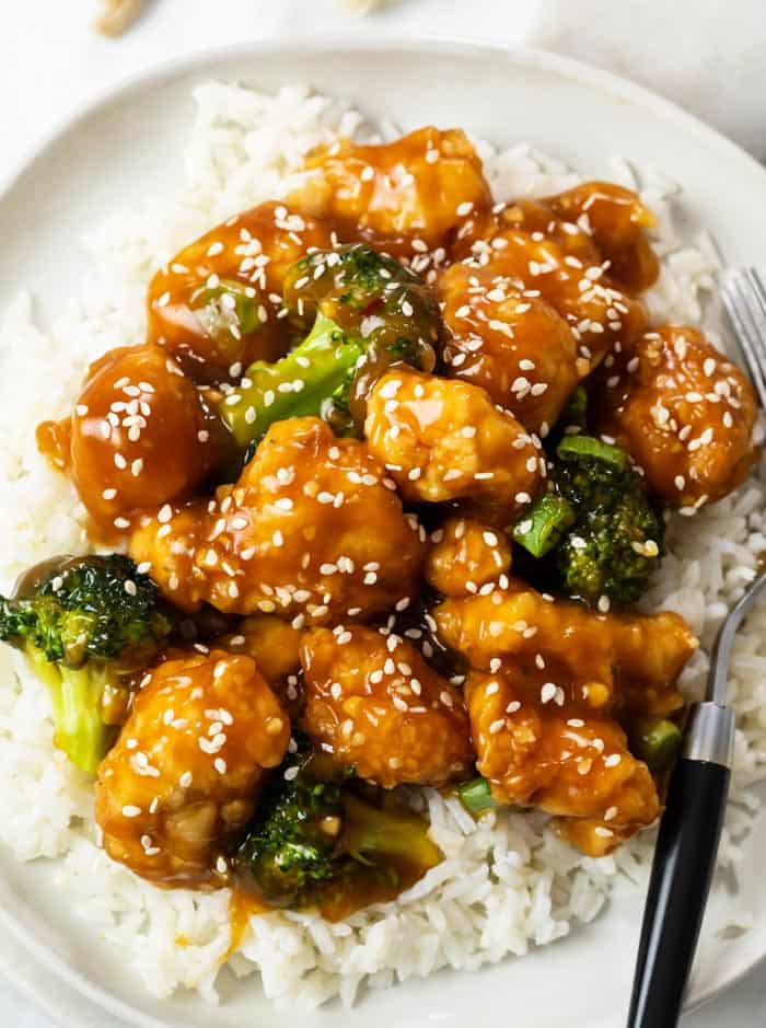 General Tso's Chicken with broccoli on a bed of white rice on a plate.