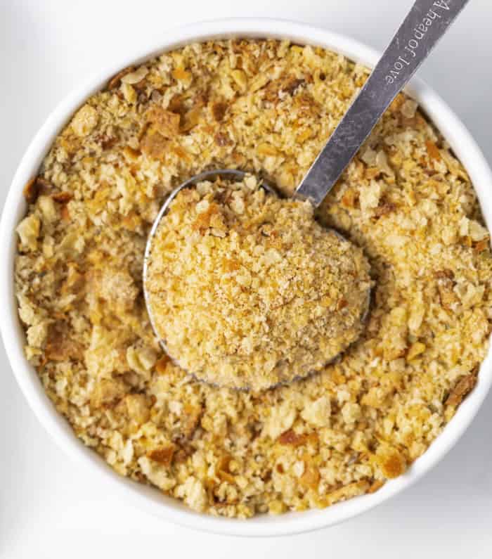 A tablespoon in a white bowl full of homemade breadcrumbs.