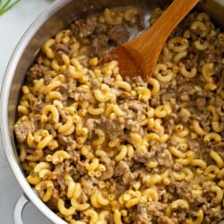A skillet of homemade Hamburger Helper with a wooden spoon.