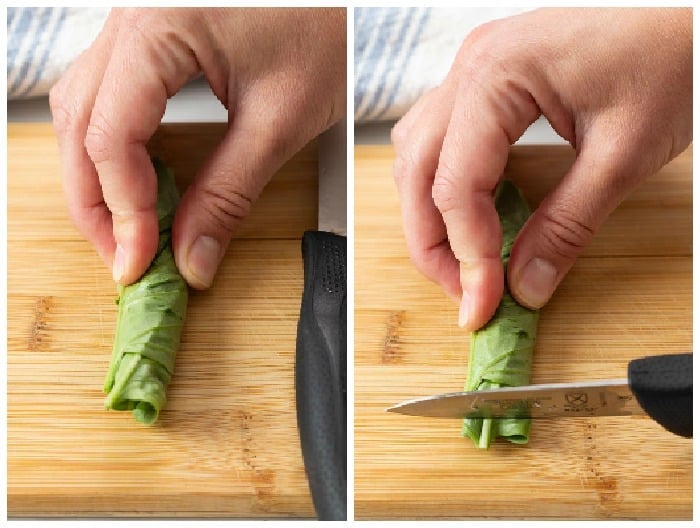 A pairing knife slicing into rolled up basil.
