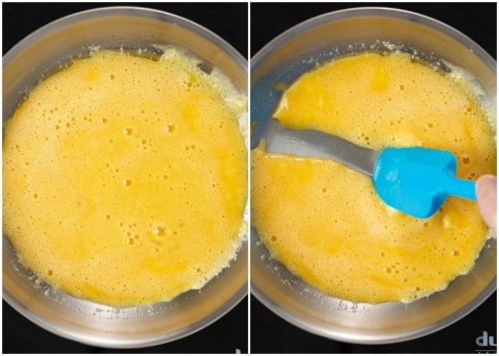 Whisked eggs in a pan with a spatula to make fluffy scrambled eggs.