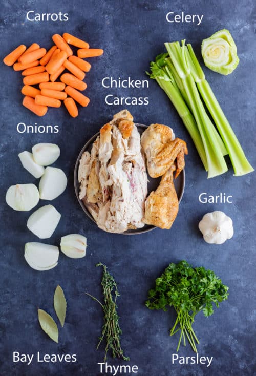 Overhead view of ingredients needed to make homemade chicken stock on a blue surface.