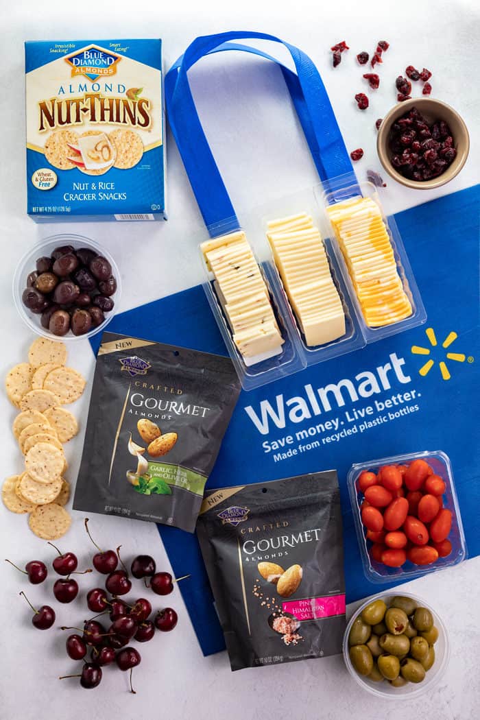 Overhead shot of Walmart bag, crackers, almonds, olives, cranberries, cherries, and tomatoes.