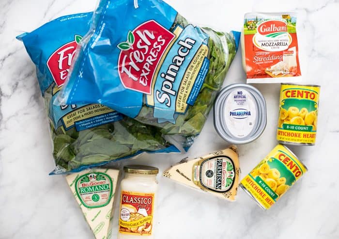 Ingredients needed to make spinach and artichoke dip recipe on a white granite countertop