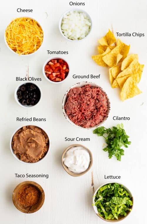 Overhead view of ingredients needed to make taco casserole on a white surface.