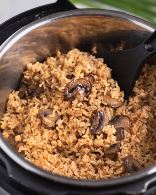 An instant pot filled with cooked brown rice and mushrooms.