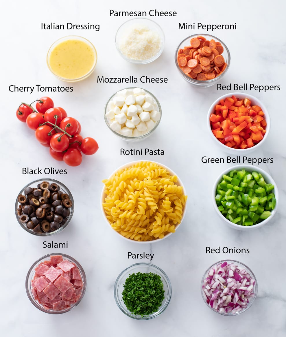 Ingredients for making Italian Pasta Salad on a white surface with labels.