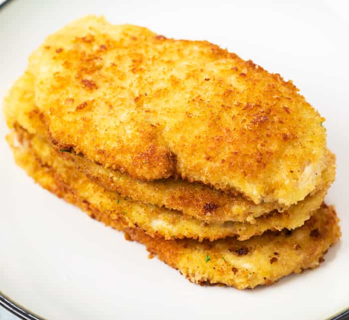 A pile of crispy golded breaded chicken on a plate for chicken milanese.