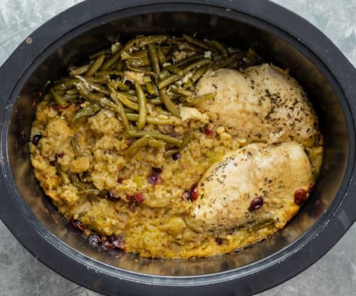 Crock Pot full of cooked stuffing, seasoned chicken, and green beans.