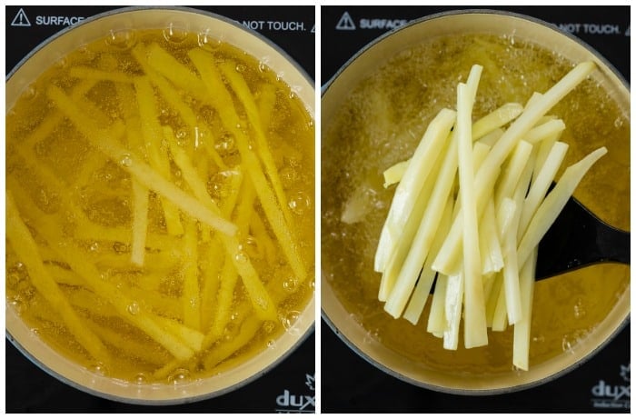 French fries in a dutch oven being fried at 300 degrees and then lifted from the oil with a slotted spoon.