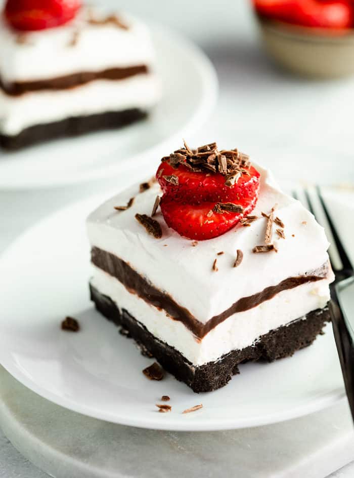 4 layered Oreo delight with a strawberry on top and chocolate shavings on a white plate. 