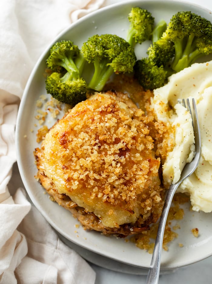 Parmesan Crusted Chicken with broccoli and mashed potatoes on a white plate with a fork.