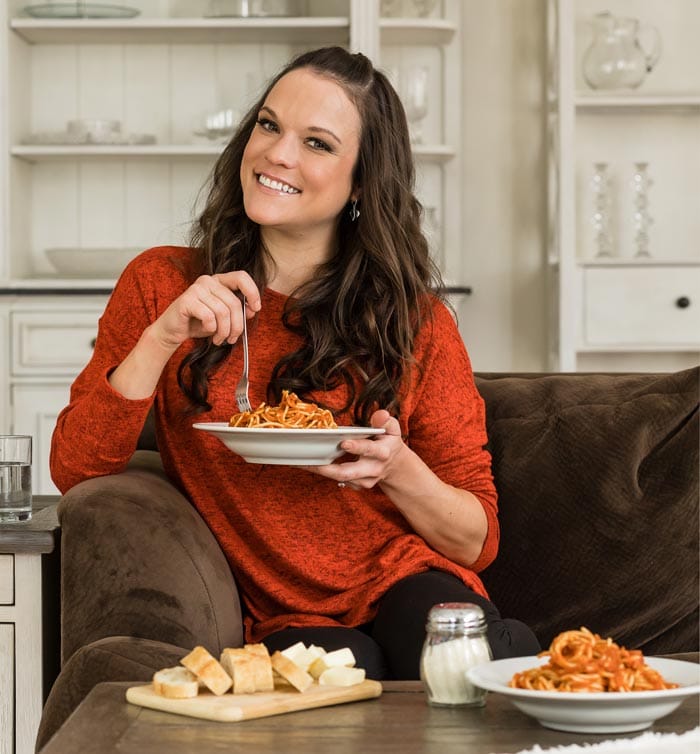 A picture of Stephanie Melchione sitting with a plate of pasta and smiling at the camera.