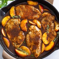 Peach Chicken in a skillet with fresh thyme and peach slices in a balsamic sauce.