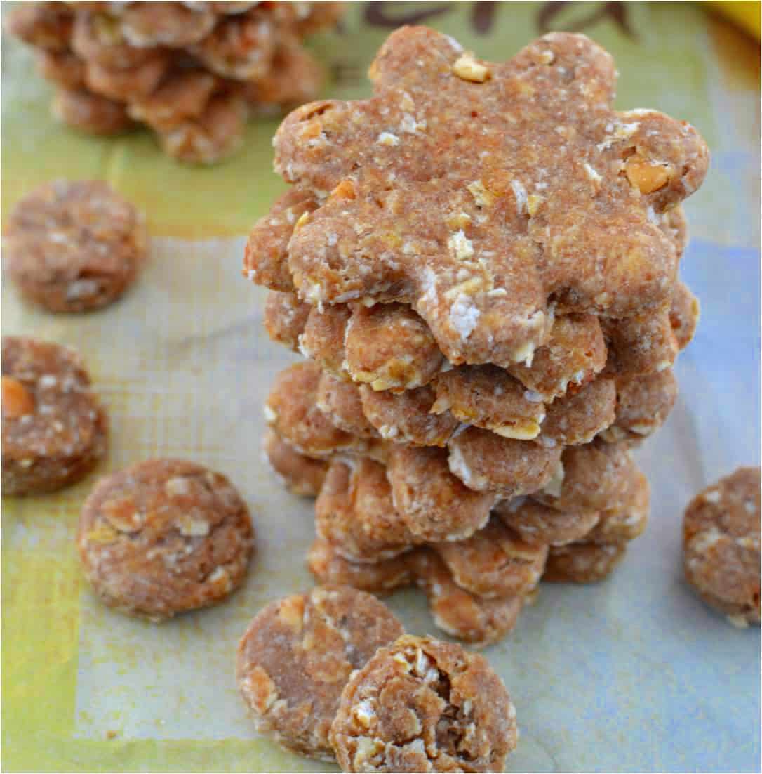a stack of homemade dog treats in a flower shape with smaller round dog treats next to it.