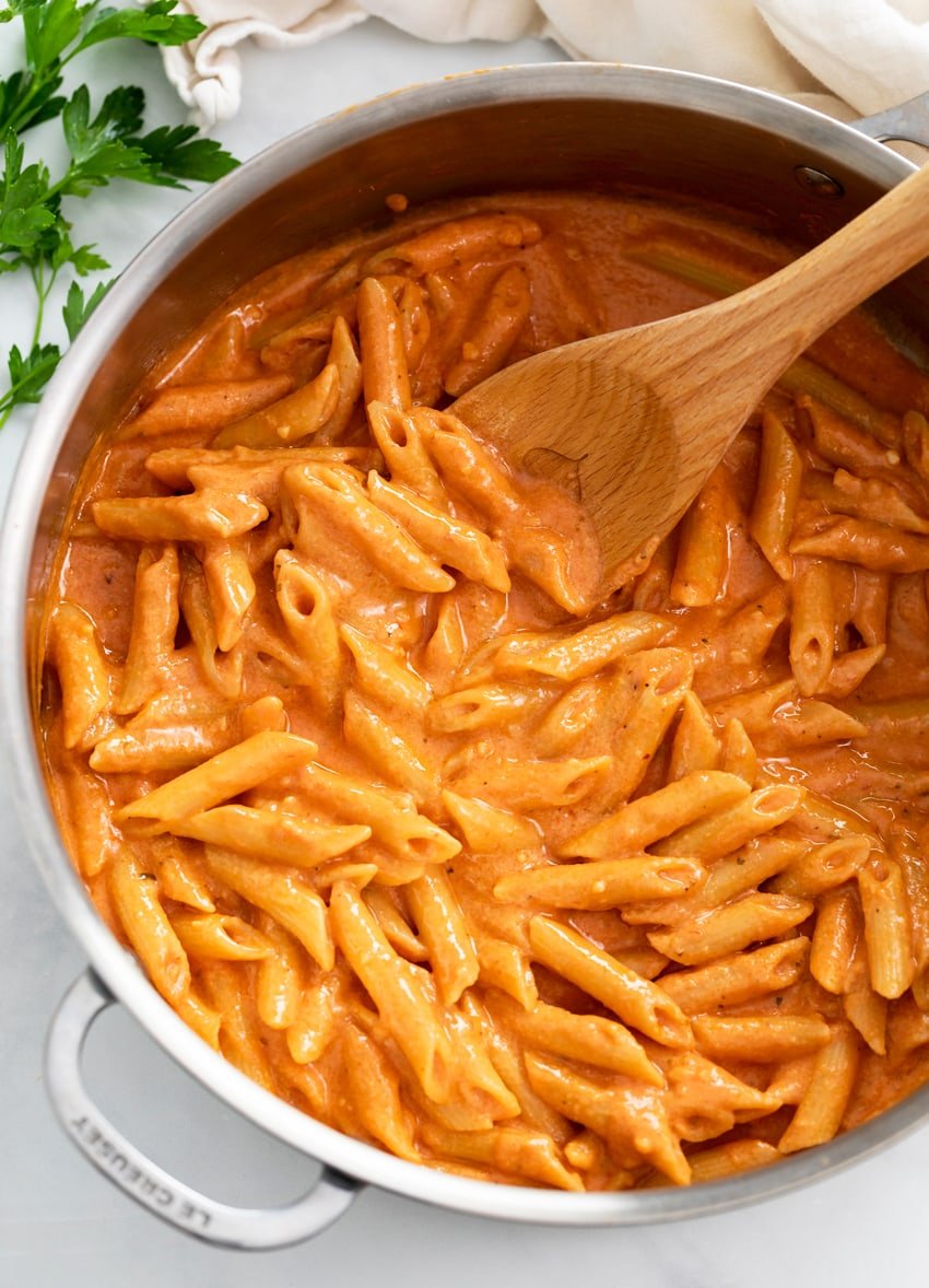 A skillet filled with Pink Sauce Pasta with a wooden spoon.