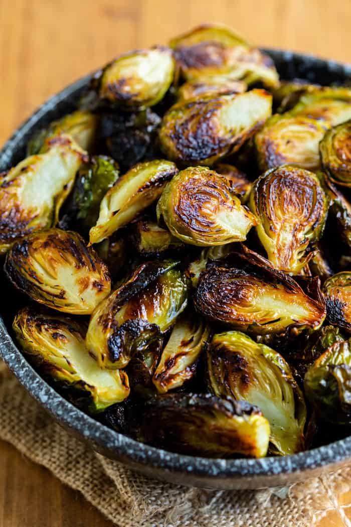 A black bowl filled with roasted brussels sprouts.