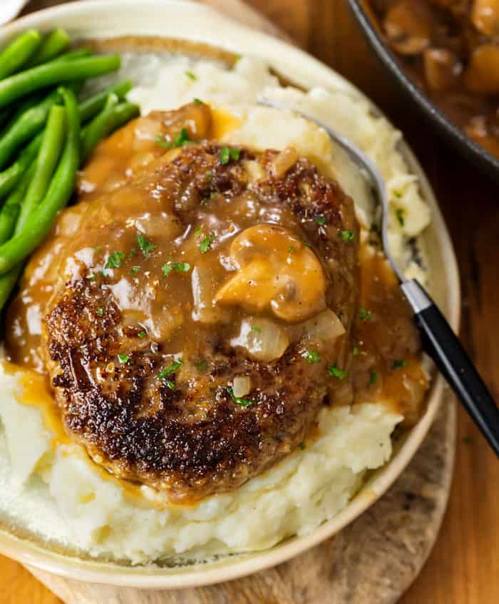 Salisbry Steak on top of creamy mashed potatoes with green beans.