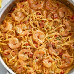 A skillet of shrimp pasta with linguine in a creamy sauce.