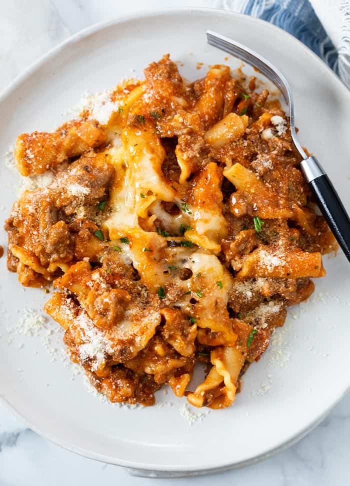 A white plate with Skillet Lasagna and melted cheese with a fork on the side.