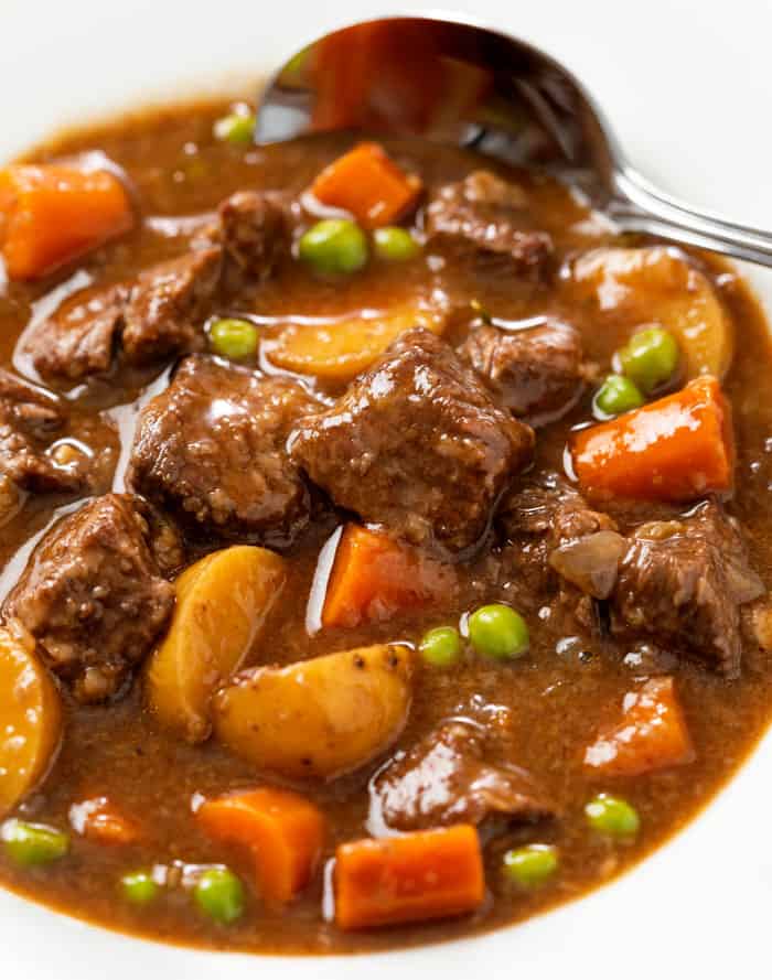 A white bowl filled with Slow Cooker Beef Stew with a spoon in the background.