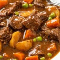 A close up view of Slow Cooker Beef Stew with beef, potatoes, carrots, peas, and red wine.