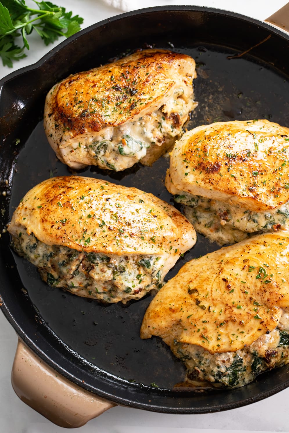 A skillet of Stuffed Chicken Breast filled with spinach, sundried tomatoes, and cheese.