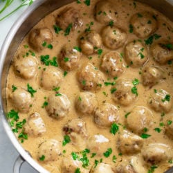 Swedish Meatballs in a skillet with a gravy cream sauce and fresh parsley.