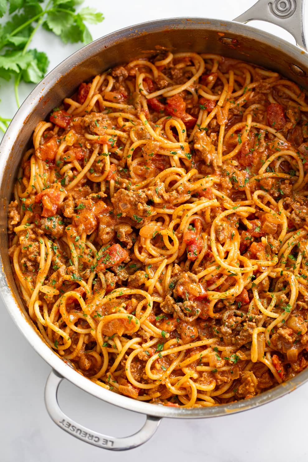 Taco Spaghetti in a skillet with taco meat and diced tomatoes with sauce.
