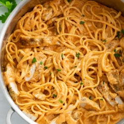 A skillet filled with Creamy Tomato Pasta with Chicken and parsley.