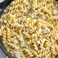 A skillet of White Cheddar Chicken Pasta with spiral pasta and a creamy white cheddar sauce with seasonings.