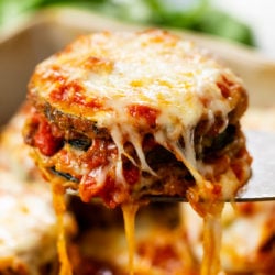 Cheesy Zucchini Parmesan with Marinara sauce and strings of cheese hanging down.