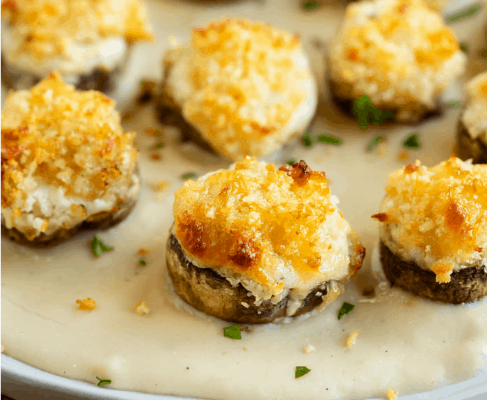 White Cheddar Stuffed Mushrooms on a plate with white sauce.